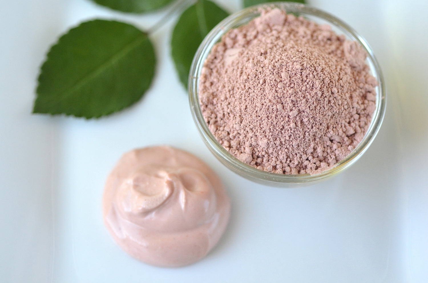 Tief reinigende kosmetische Bentonit (Montmorillonit) Rosa Tonerde für Beauty Spa Gesichtsmaske, Körper Detox und Haarbehandlungen. Lehm und Aktivkohle Pulver und Maske in Glasschale.