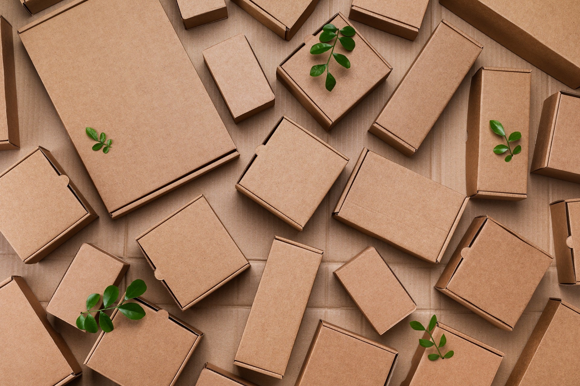 Viele Pappkartons aus natürlichen wiederverwertbaren Materialien mit grünen Blättern sprießen von oben. Verantwortungsbewusster Konsum, umweltfreundliche Verpackung, weniger -Abfall-Konzept.